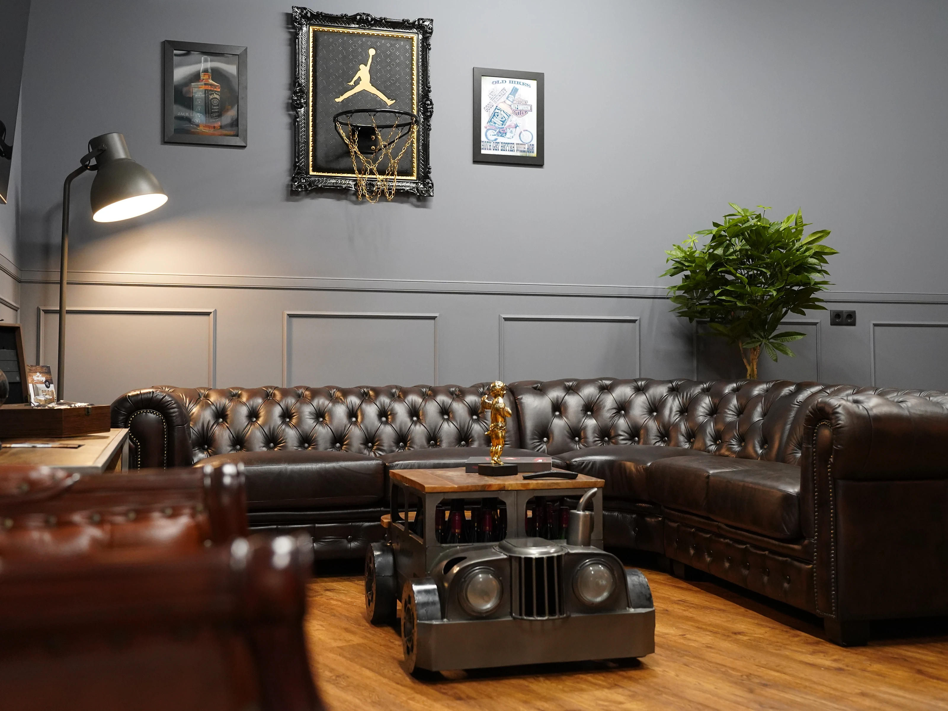 Modernes Tattoo‑Studio: gepolsterter Tätowierstuhl, Arbeitsplatz, Leuchte und Wandmotive in sauberer, professioneller Atmosphäre