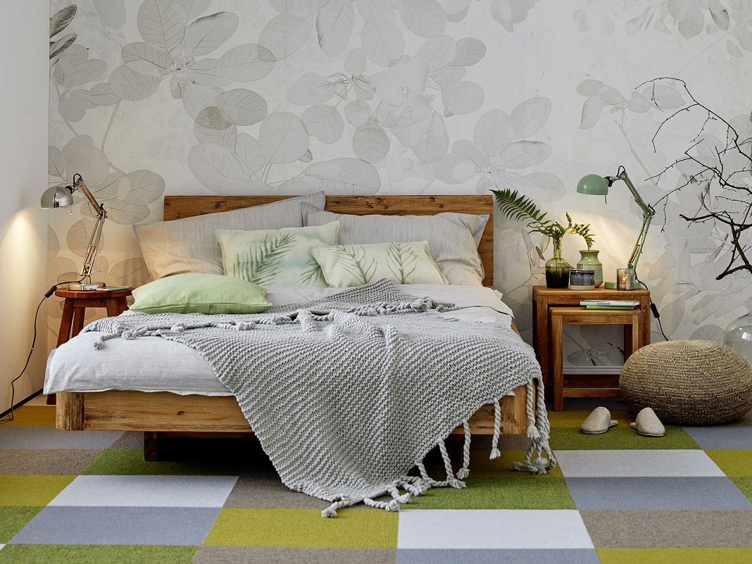 Hölzerner Nachttisch neben Bett in warmem Schlafzimmer mit Lampe und Deko, skandinavischer Stil, helle Holz- und Beigetöne