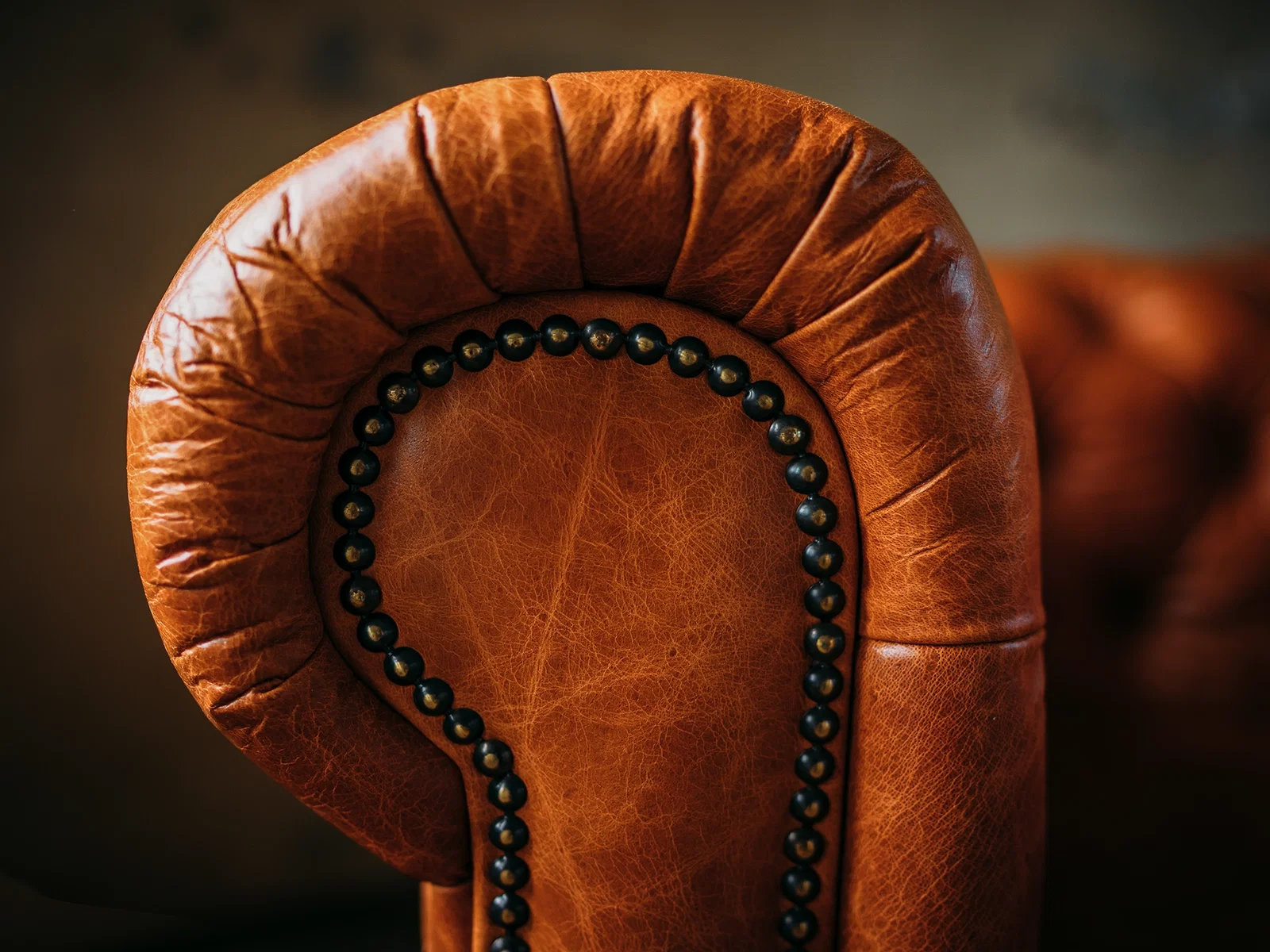 Klassisches Chesterfield-Sofa aus dunklem Leder mit Knopfheftung, im eleganten Wohnzimmerambiente – Vintage 3‑Sitzer.