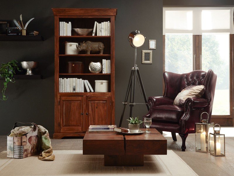 Gemütliche Advents-Szene mit Massivholz-Couchtisch Amberley, Kerzen, Tannenzweigen und warmem Lichterglanz im Wohnzimmer.