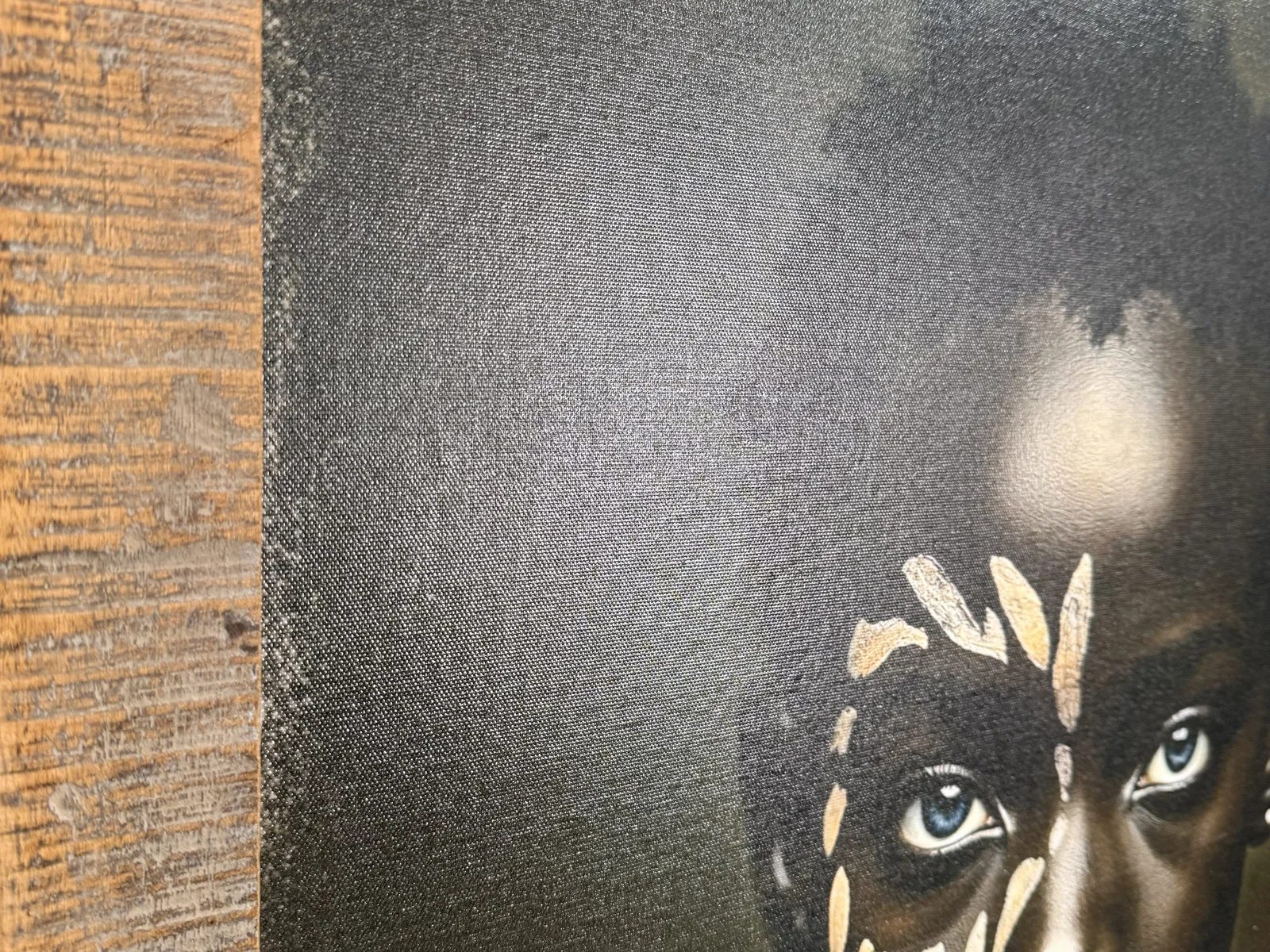 Canvas-Wandbild 70×90 Silent Strength aus Altholz in 45°-Ansicht, Gesichtsporträt mit weißer Stammesbemalung und blauen Augen.
