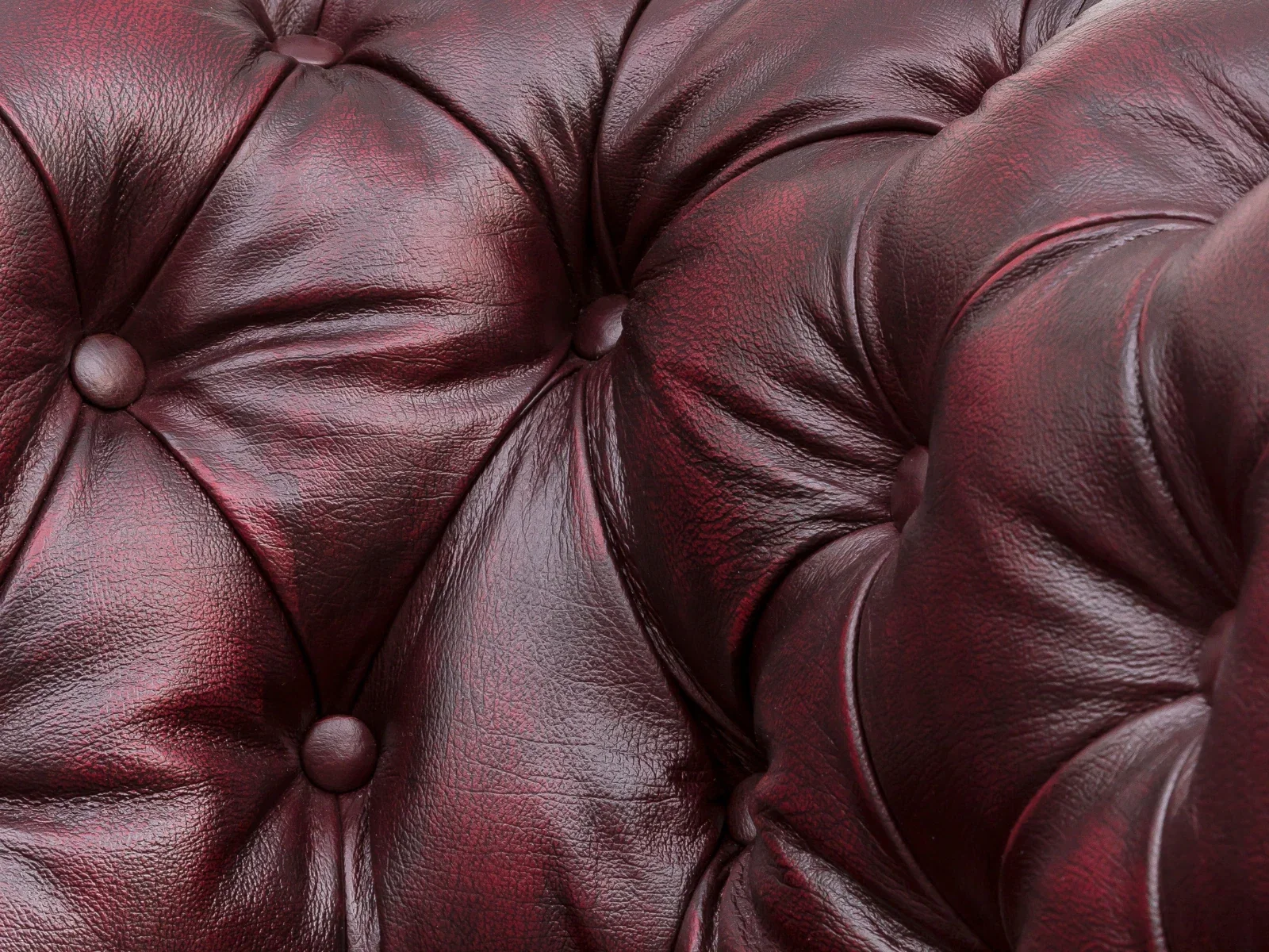 Rotes Leder mit Patina in Nahaufnahme: natürliche Maserung und gealterte Textur, ideal als Polster- und Möbelbezug.