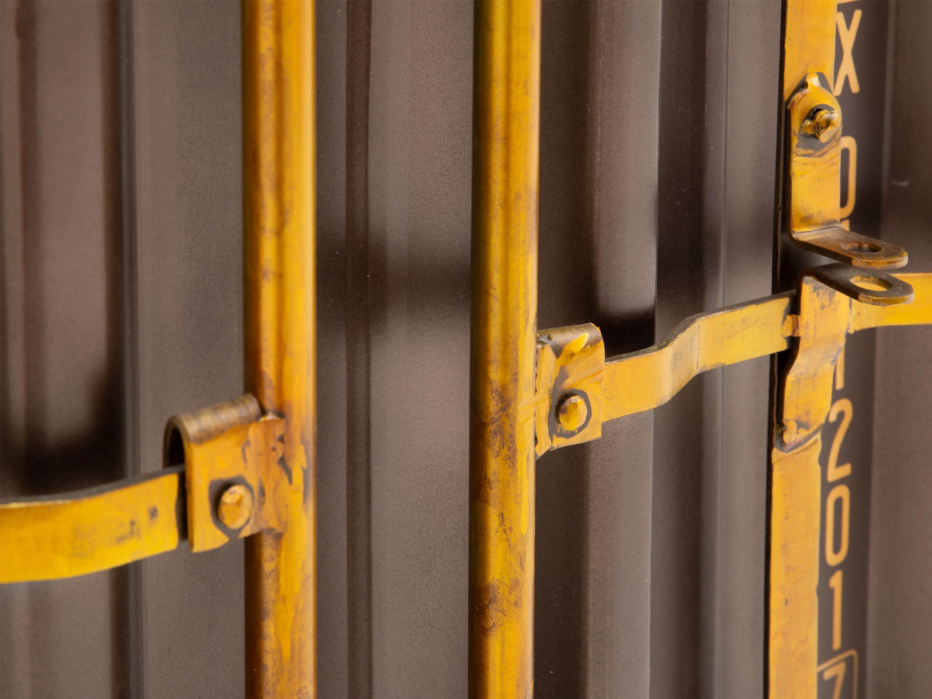 Detailbild eines gelb lackierten Metallverschlusses an braun geriffelter Metalltür (Frontansicht)