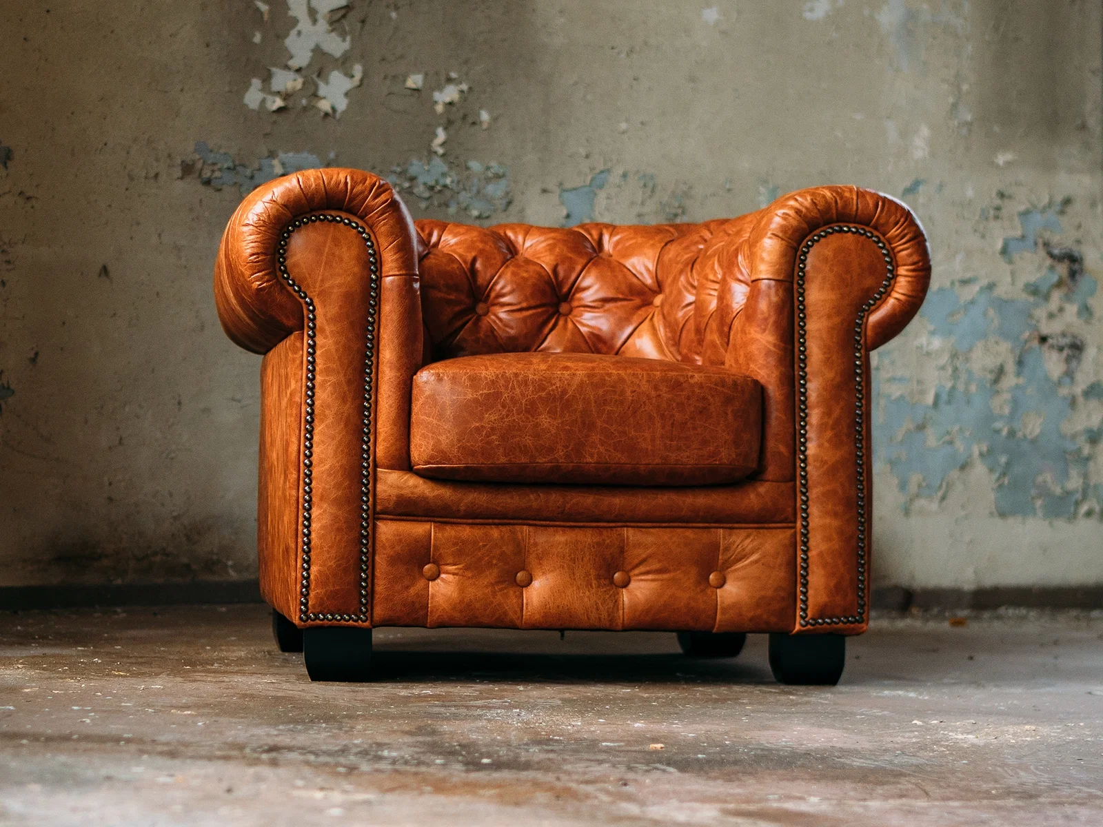 Klassisches Chesterfield-Ledersofa in gemütlichem Vintage-Ambiente, tief gesteppt mit Holzfüßen – elegantes Wohnzimmer-Sitzmöbel
