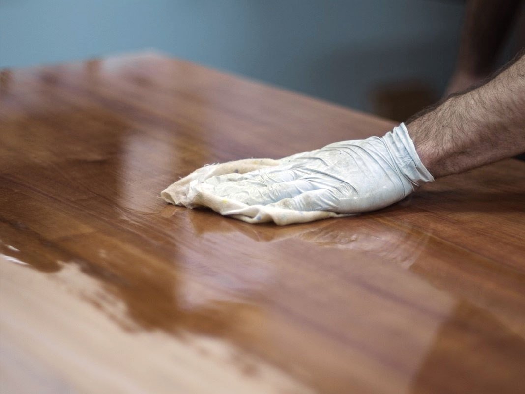 Ratgeber 'Massivholz ölen' – Nahaufnahme geölter Holzoberfläche mit Ölflasche und Pinsel, warme Holzmaserung, natürliche Pflegehinweise für Massivholzmöbel