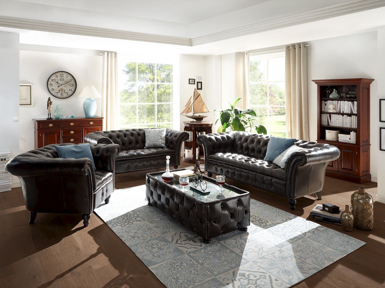 Traditionelles englisches Chesterfield-Ledersofa mit passendem Sessel in warmem, klassischem Wohnraum mit Holzakzenten