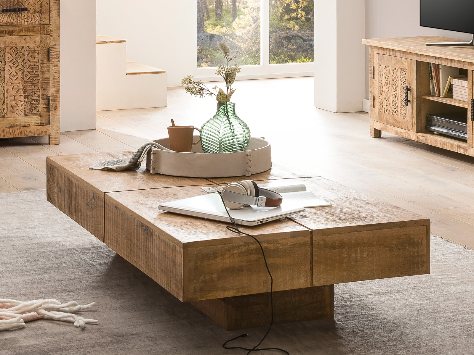 Couchtisch Amberley Mango 80×80×30 cm aus lackiertem Mangoholz in natur, 45°-Ansicht als Wohnbeispiel mit Glasvase, Dekotablett und Laptop.