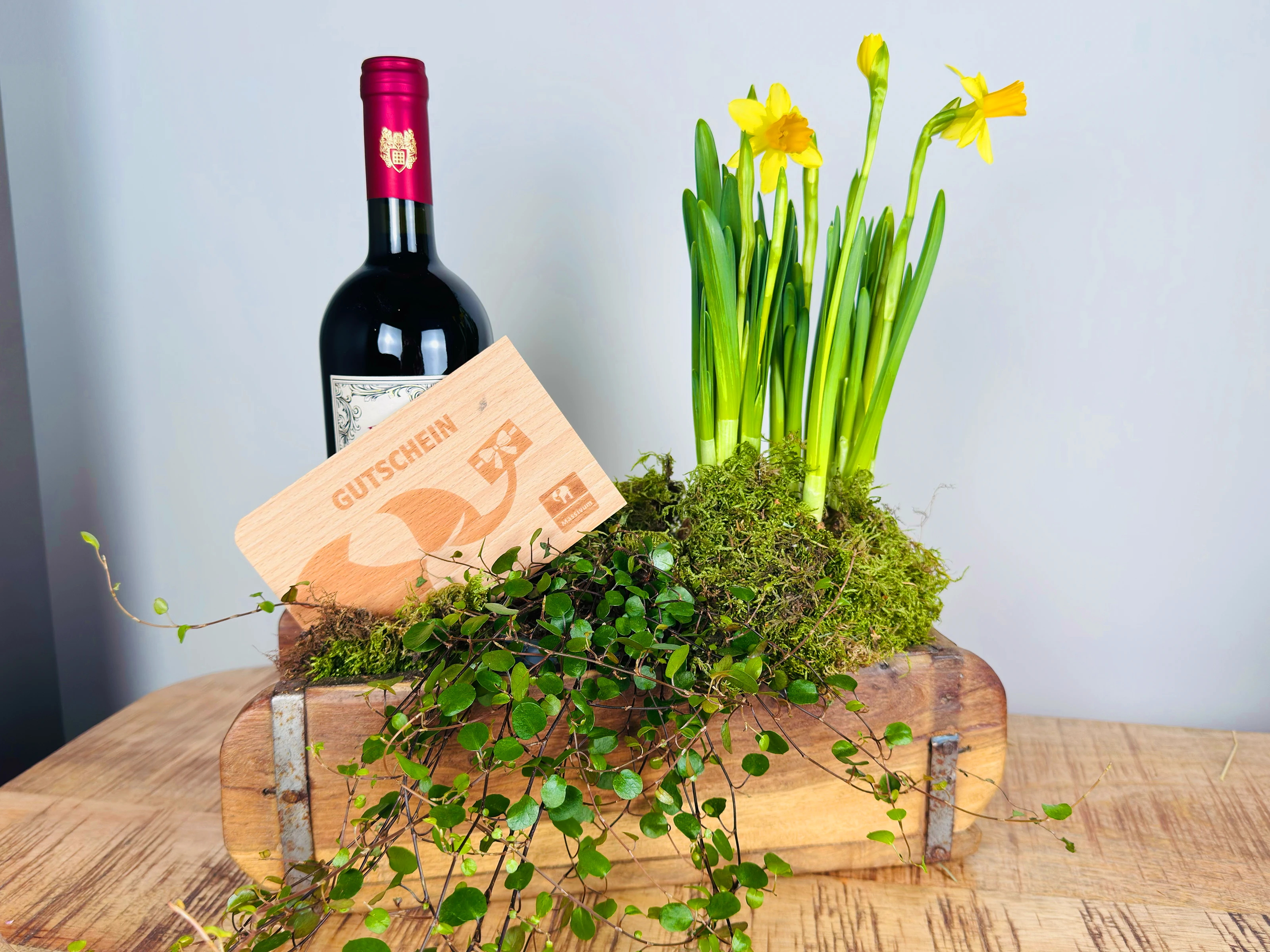 Osterdekoration mit bemalten Eiern, Frühlingsblumen und rustikalem Holzuntergrund – frühlingshafte, warme Stimmung für Ostertisch
