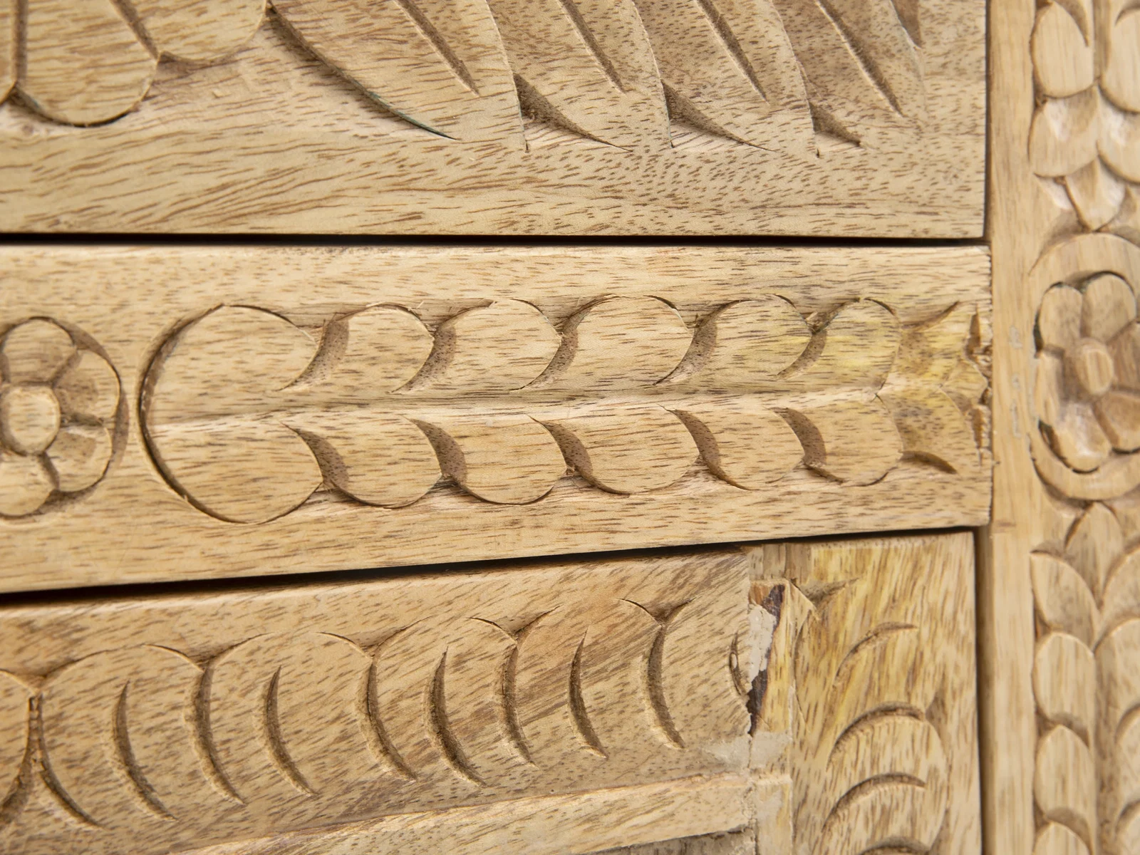 Detailaufnahme von geschnitztem Massivholz mit floralem Muster und natürlicher Maserung in warmem Braunton