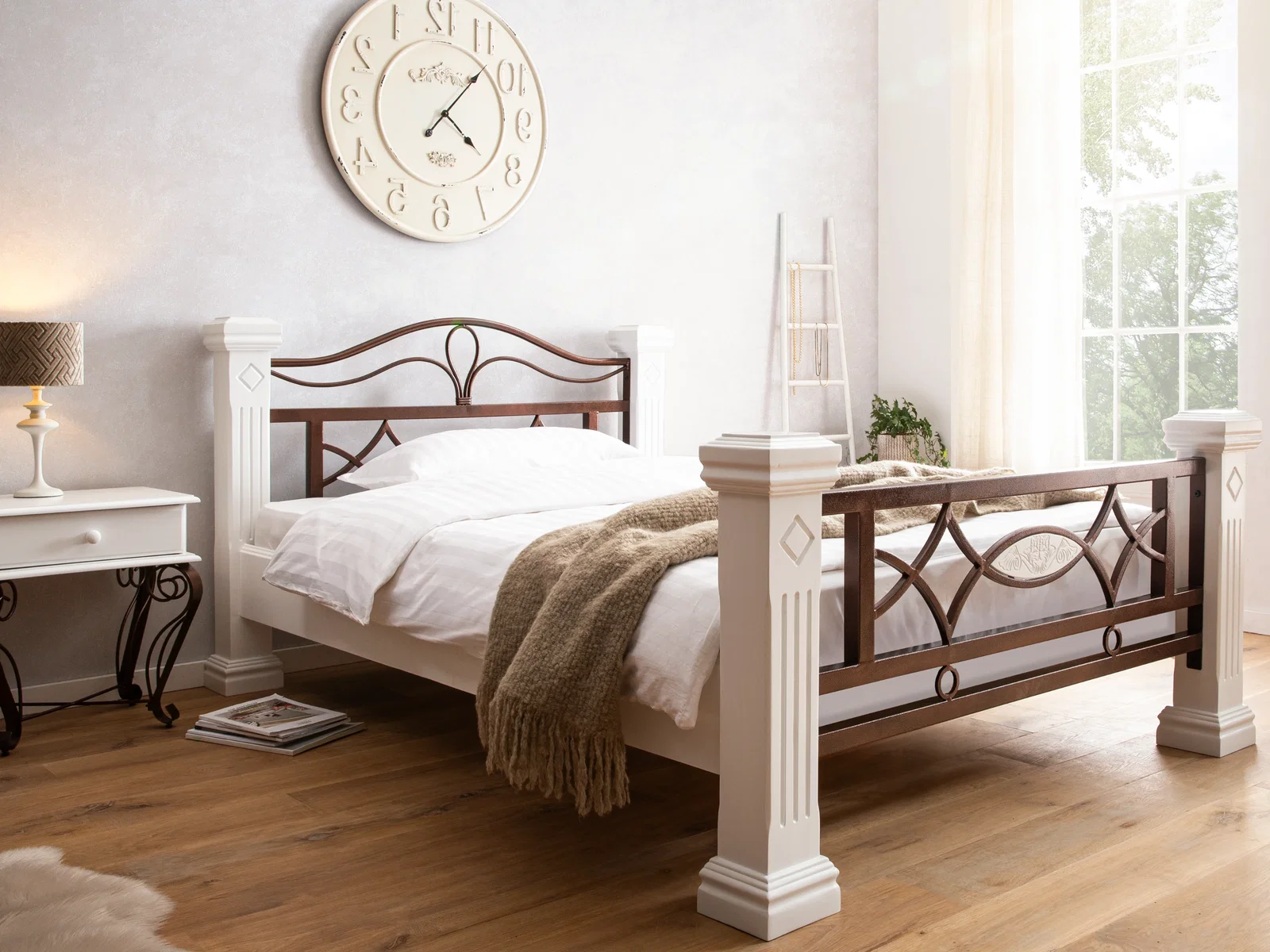 Bett im Materialmix aus weißem Holz und dunklem Metall mit dekorativem Kopf- und Fußteil in einem hellen Schlafzimmer.