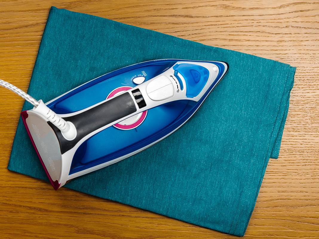 Nahaufnahme: Ausbügeln‑Technik zur Holzmöbel‑Aufarbeitung mit Tuch und erhitztem Werkzeug auf sichtbarer Holzmaserung