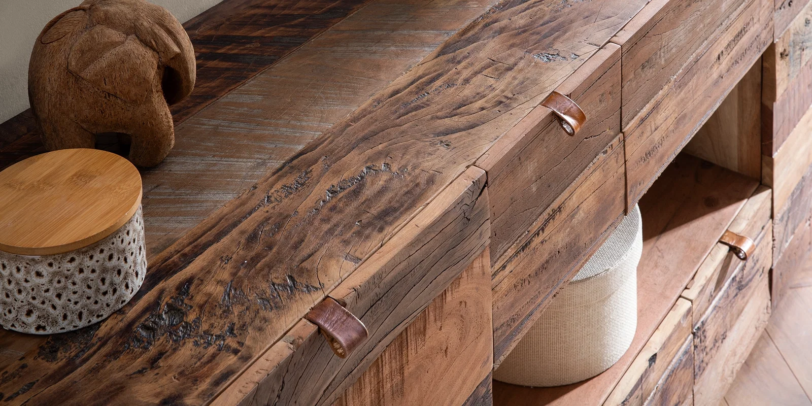 Detailaufnahme eines rustikalen Sideboards aus Altholz mit markanter Maserung, Ledergriffen und offenen Fächern