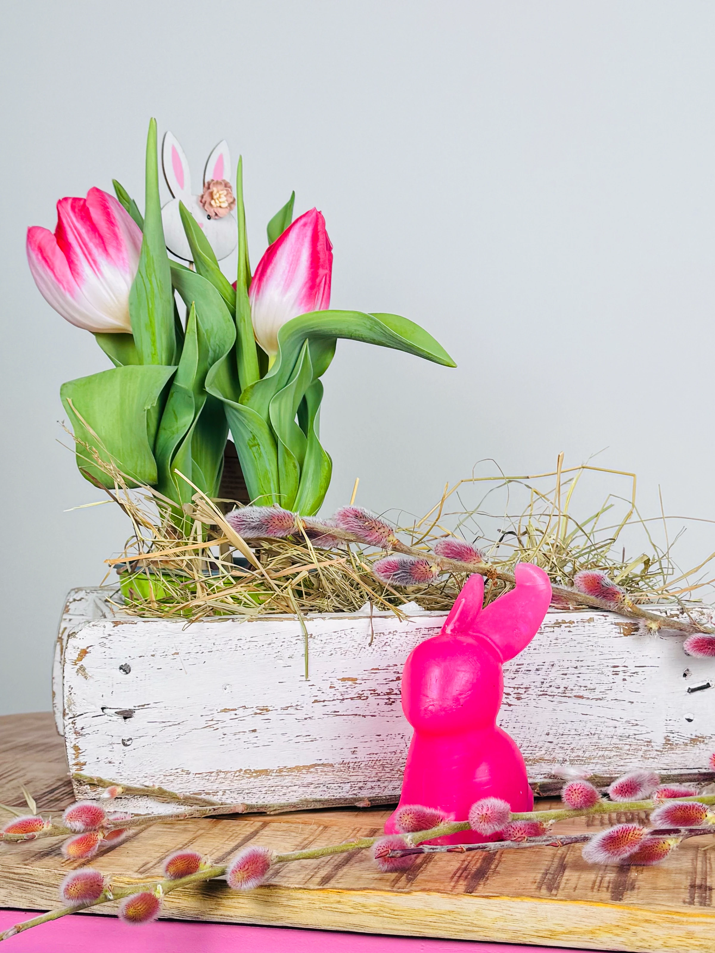 Frühlingshafte Osterdekoration: pastellfarbene Ostereier und Holzdeko auf rustikalem Holztisch, warme, einladende Stimmung